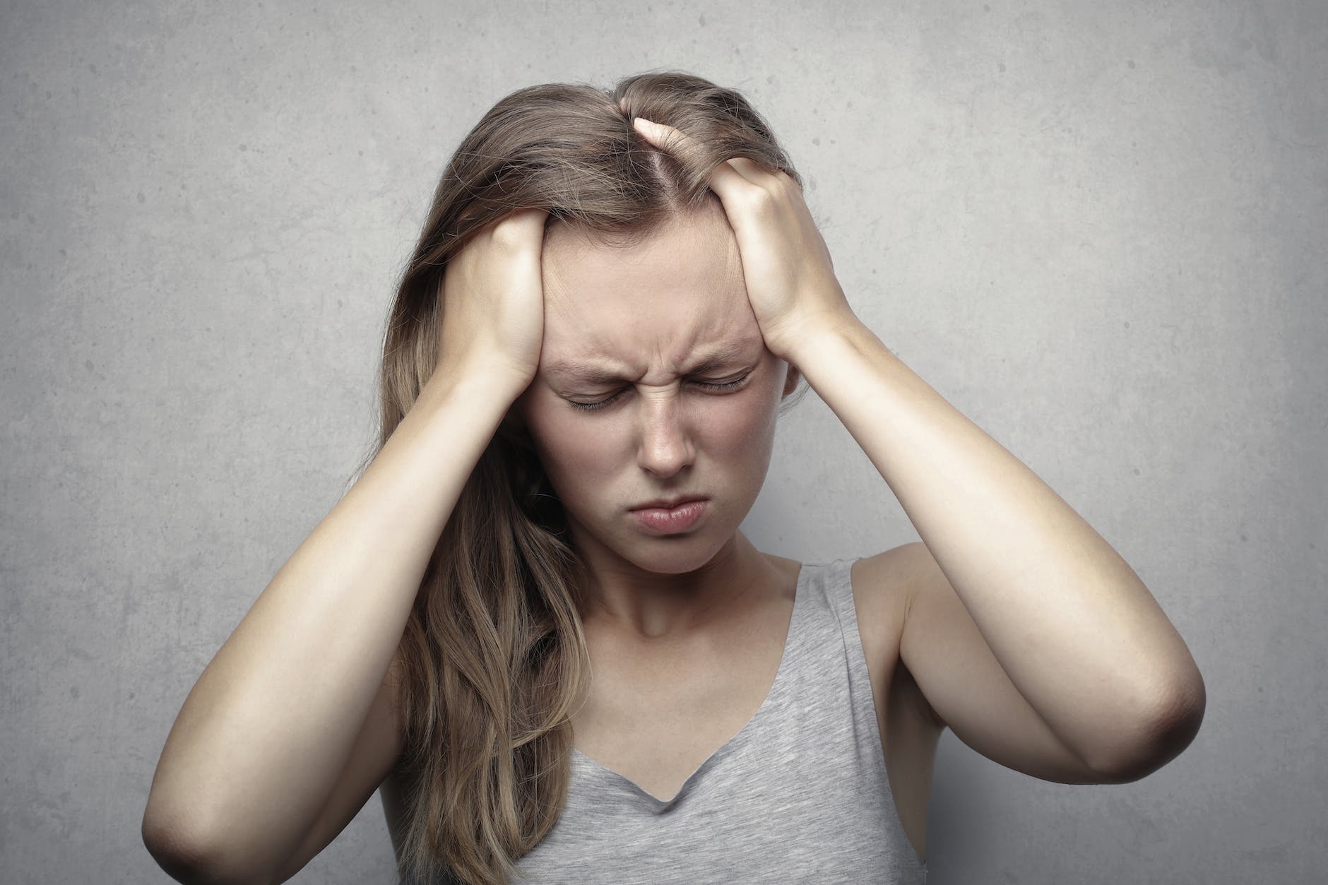 Hair loss from stress: woman in gray tank top showing distress