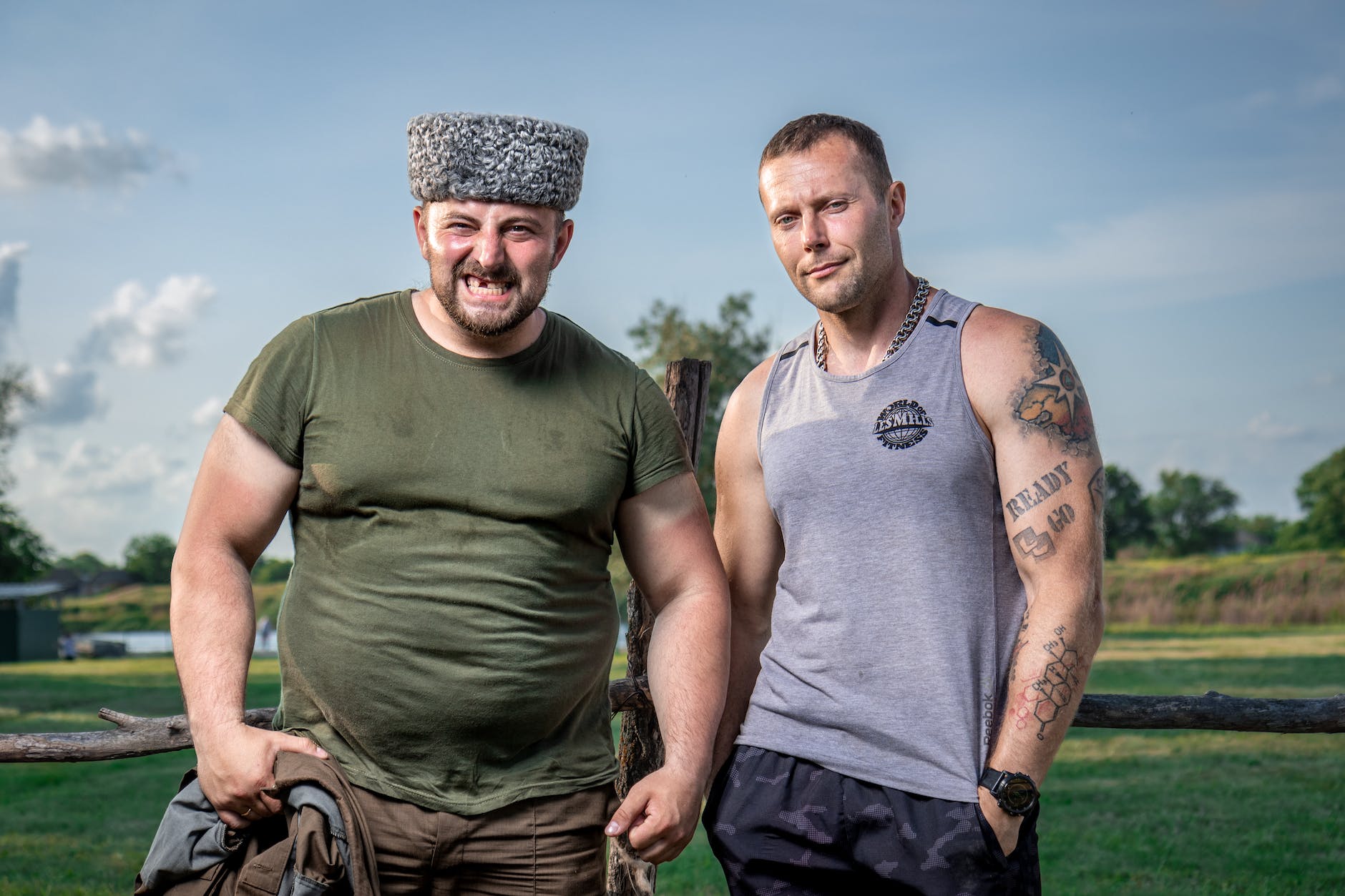 sweaty men posing together in front of wooden fence